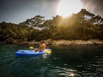 Man rowing boat in lake against sky during sunset