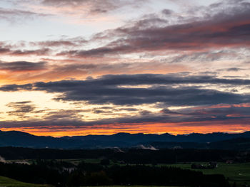 Scenic view of dramatic sky over silhouette landscape during sunset