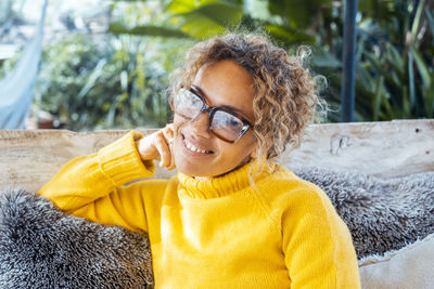 Portrait of young woman wearing sunglasses while sitting outdoors