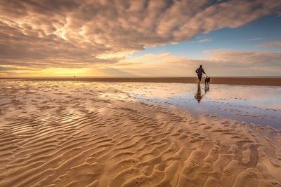 Man standing on beach against sky during sunset