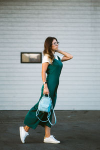 Full length of woman standing against wall