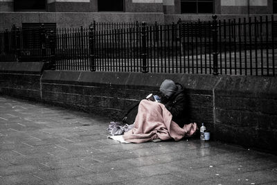 Beggar sitting on street against wall