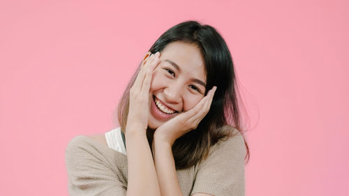 Portrait of a smiling young woman against pink background