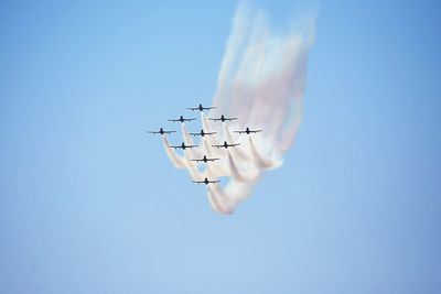 Low angle view of airplane flying against clear blue sky
