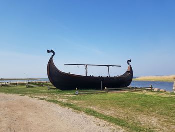 Ship moored on beach against clear blue sky