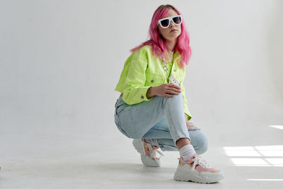 Portrait of young woman standing against wall