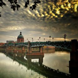 Bridge over river against cloudy sky