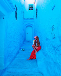 Girl with a cat sitting on a street of the blue city chefchaouen in morocco