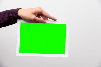 Cropped hand of woman holding adhesive note against blue background