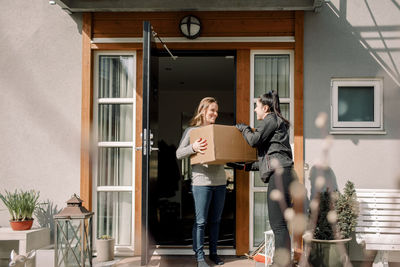 Female customer receiving box from young delivery woman