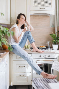 Full length of woman sitting at home