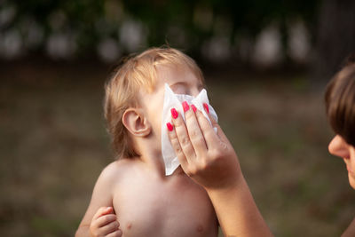 Portrait of shirtless boy holding camera
