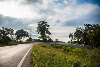 Road by trees against sky