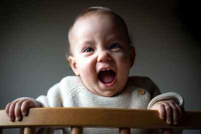 Waist up portrait of little laughing baby with blond hair watching at camera