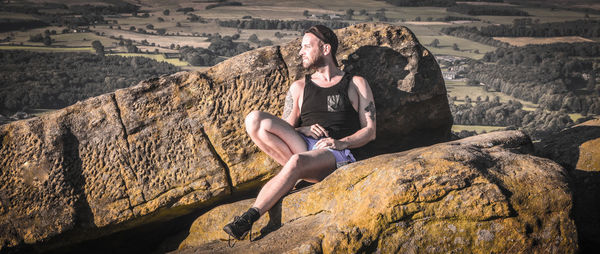 Full length of young man sitting on rock