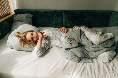 Beautiful woman in pajamas lies on the bed in the morning.