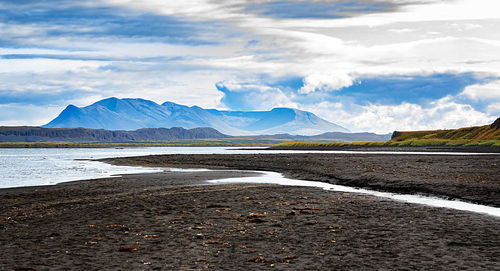 Scenic view of road by mountains against sky