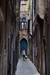 Rear view of woman walking in alley