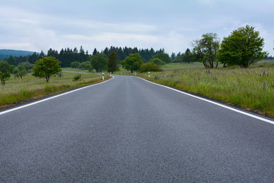 Empty country road between green nature and with sky