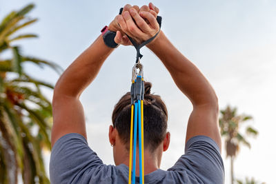 Low section of man holding rope against sky