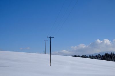 Snow covered landscape against blue sky