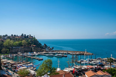 High angle view of townscape by sea against clear blue sky