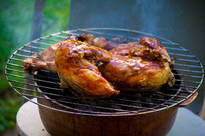 High angle view of chicken meat cooking on metal grate