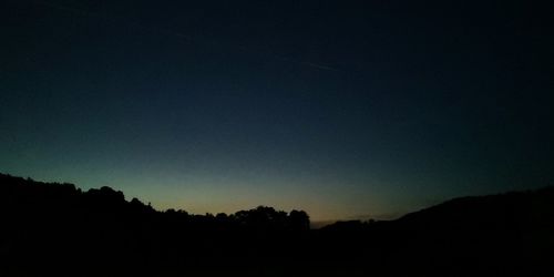 Low angle view of silhouette trees against clear sky at night