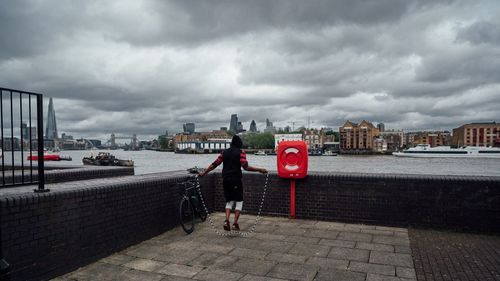 People walking in city against cloudy sky