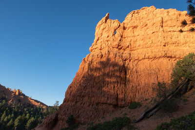 Low angle view of rock formation against clear blue sky