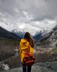 Rear view of woman standing on snow against mountains