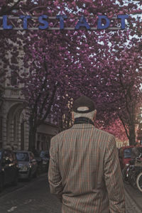 Rear view of man standing by flowers in city