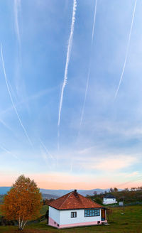 Scenic view of vapor trails over buildings against sky