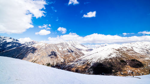 Scenic view of snow covered mountains against blue sky