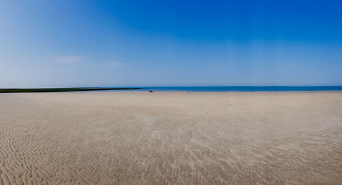 Scenic view of beach against blue sky