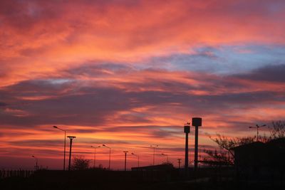 Silhouette street lights against dramatic sky during sunset