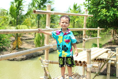 Portrait of smiling cute boy standing on footbridge