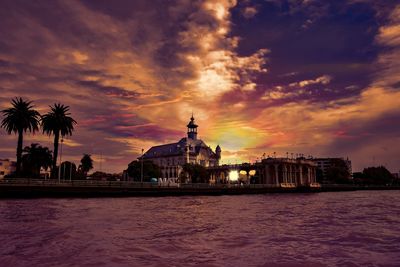 View of buildings by sea against sky during sunset