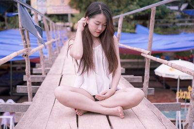 Beautiful young woman sitting on footbridge