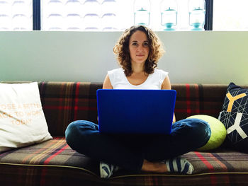 Portrait of young woman sitting on sofa