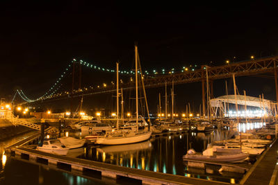 Illuminated suspension bridge over river in city at night