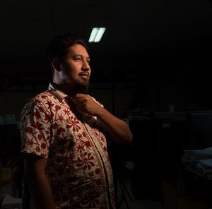 Young man looking away while standing in the dark