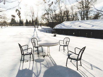 Empty chairs and tables on snow covered landscape