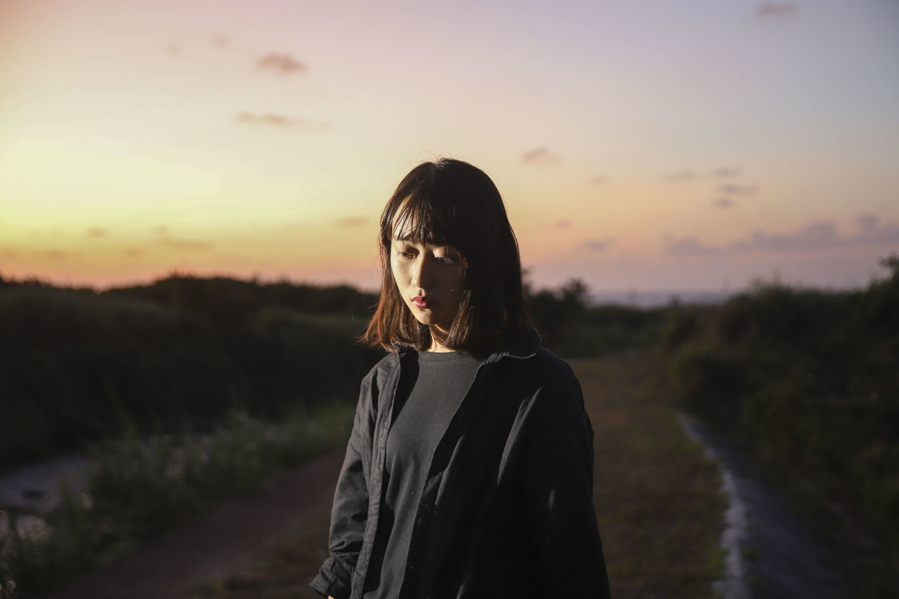 WOMAN STANDING ON LAND AGAINST SKY