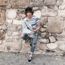 Portrait of teenage boy standing against stone wall