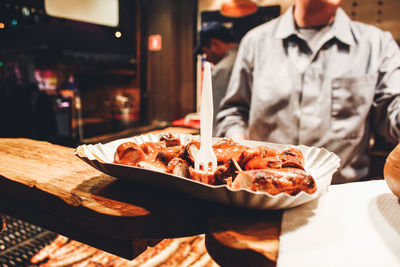 Close-up of currywurst served in plate with sitting at table