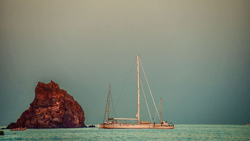 Sailboats on sea against clear sky