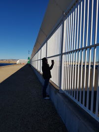 Woman standing on railing against clear sky