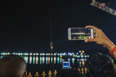 Close-up of man photographing illuminated smart phone at night