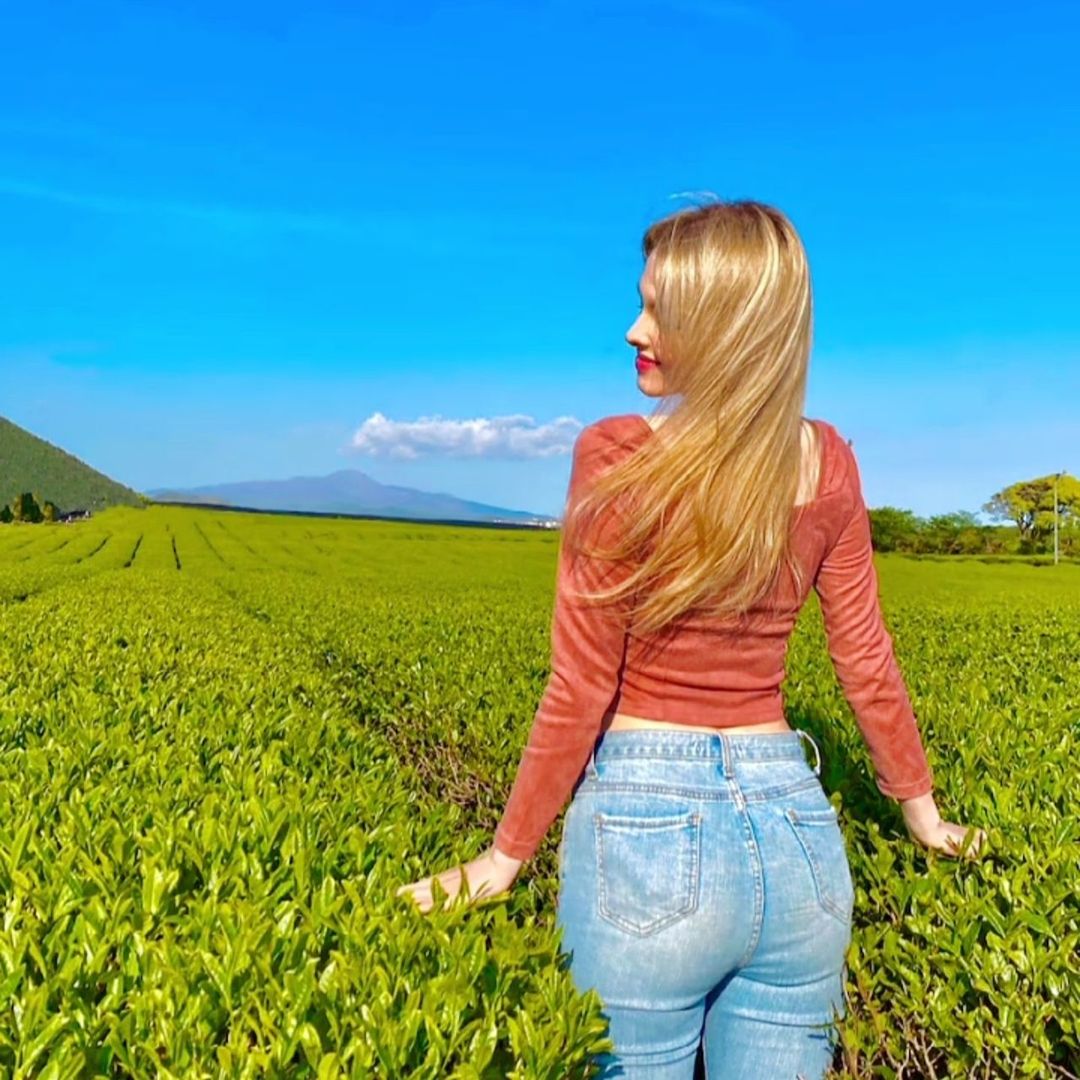 one person, landscape, field, environment, adult, women, grass, rural scene, land, sky, nature, meadow, agriculture, plant, blond hair, grassland, young adult, crop, blue, beauty in nature, casual clothing, three quarter length, green, yellow, standing, flower, hairstyle, scenics - nature, rapeseed, tranquility, rear view, long hair, day, outdoors, lifestyles, rural area, summer, tranquil scene, growth, copy space, leisure activity, farm, person, non-urban scene, fashion, female, jeans, prairie, sunlight, emotion, clothing, looking, horizon, environmental conservation, vegetable, idyllic, produce, cereal plant, happiness, smiling, sunny, portrait, natural environment, relaxation, contemplation